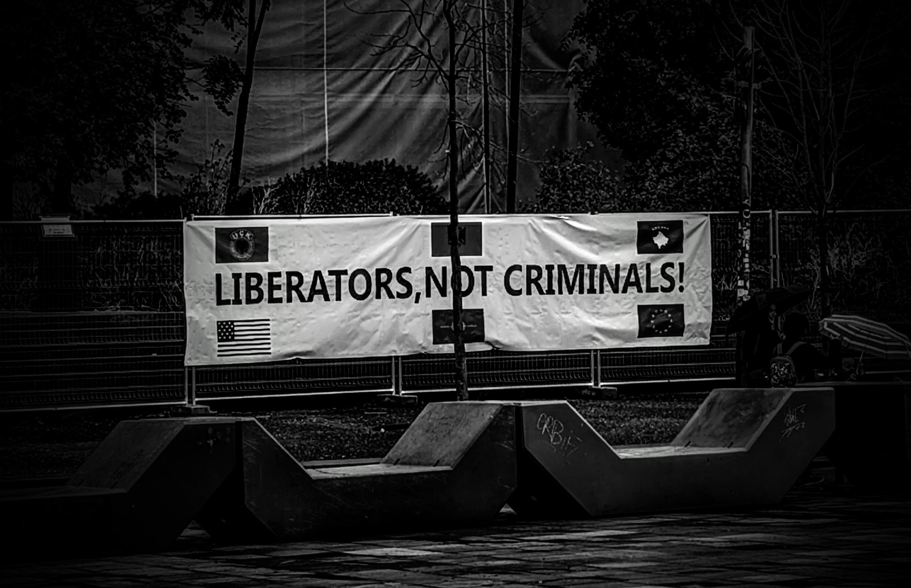 Photographie de la banderole "Liberators, not criminals !" affichée sur la Place Skanderbeg à Tirana, octobre 2025.